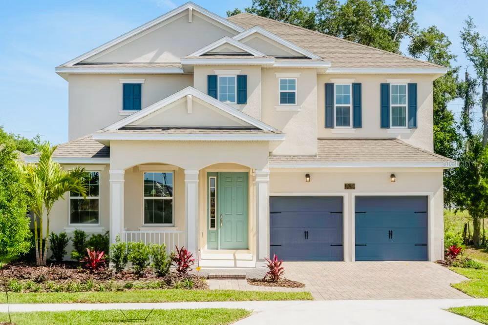 A two-story house with a light-colored stucco exterior, blue shutters, and a two-car garage — 15075 TEA TREE DRIVE, WINTER GARDEN, FL