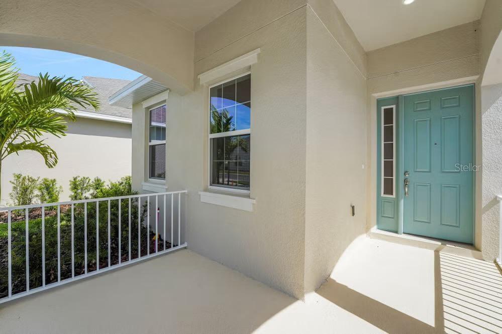 A covered front porch with a light blue door and white railings — 15075 TEA TREE DRIVE, WINTER GARDEN, FL