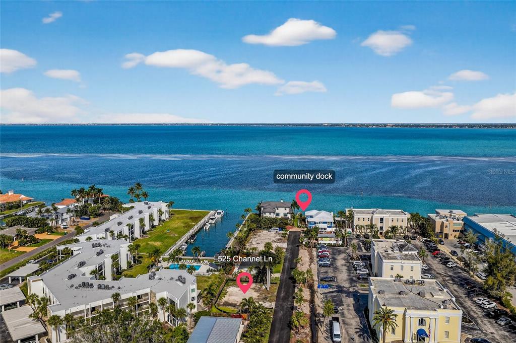 An aerial view shows a vacant waterfront lot situated between residential buildings and a dock — 525 CHANNEL LANE, LONGBOAT KEY, FL
