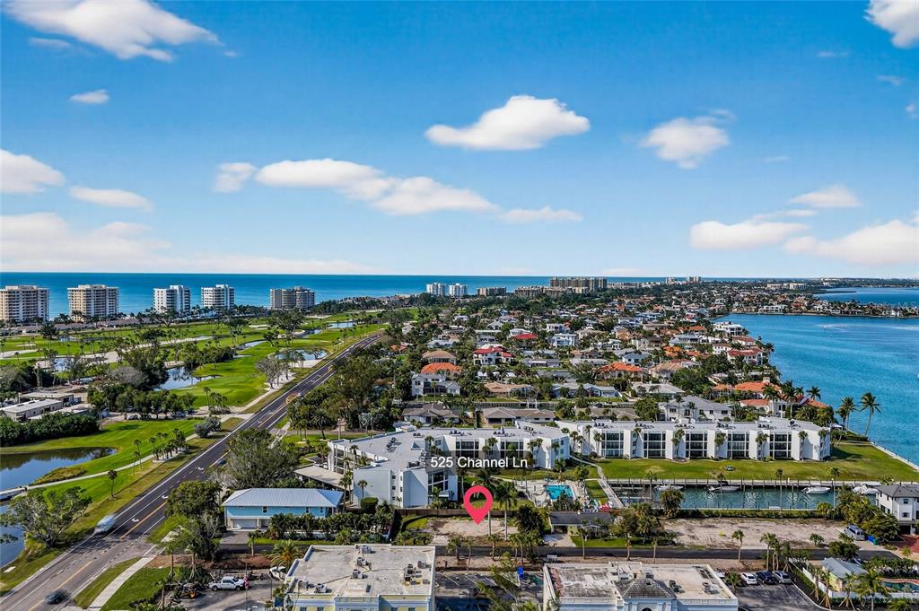 An aerial view shows a coastal residential area with a multi-story building and a pool — 525 CHANNEL LANE, LONGBOAT KEY, FL