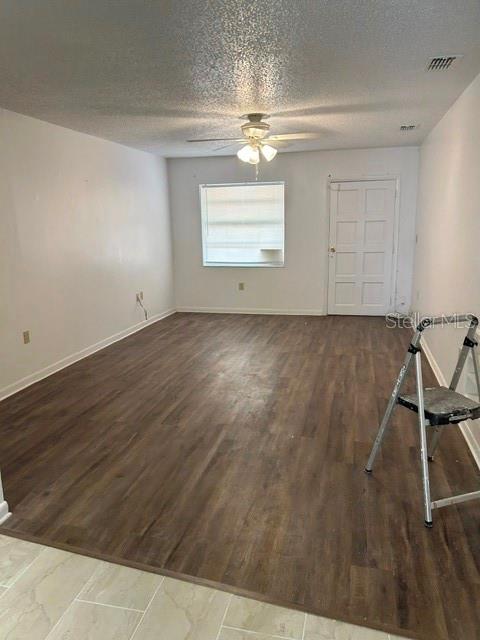 An empty room features wood-look flooring, a ceiling fan, a window, and a white door — 1472 N MELROSE DRIVE, AVON PARK, FL
