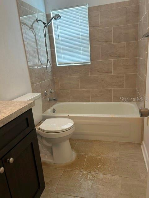 A bathroom features a toilet, a bathtub with a shower head, and beige tiled walls — 1472 N MELROSE DRIVE, AVON PARK, FL