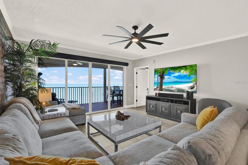 A living room features a gray sectional sofa, a marble coffee table, and a balcony view — 16450 GULF BOULEVARD UNIT 763, NORTH REDINGTON BEACH, FL