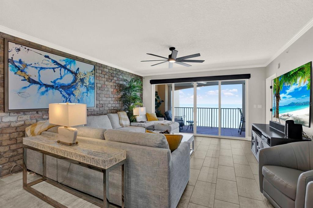 A living room features a brick accent wall, a large sectional sofa, and a balcony — 16450 GULF BOULEVARD UNIT 763, NORTH REDINGTON BEACH, FL