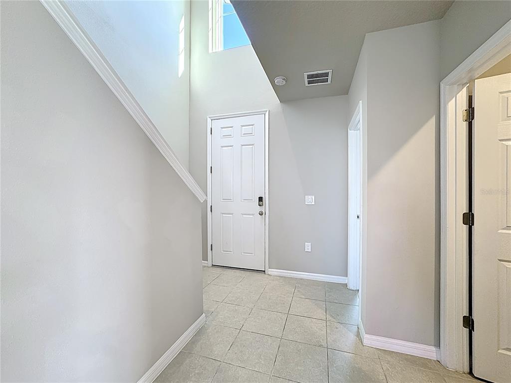 An entryway with tile flooring, a white front door, and a staircase to the left — 5251 MEREDREW LANE, ST CLOUD, FL