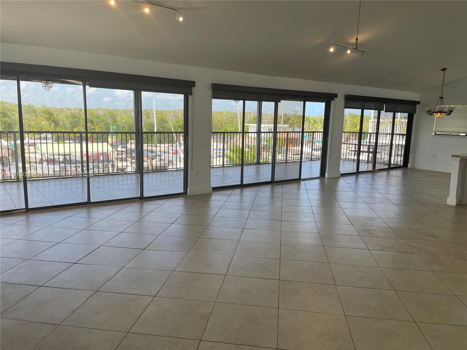 A spacious room with large sliding glass doors, tile flooring, and a view of boats — 26 S Exuma Rd # B, Key Largo FL 33037, KEY LARGO, FL