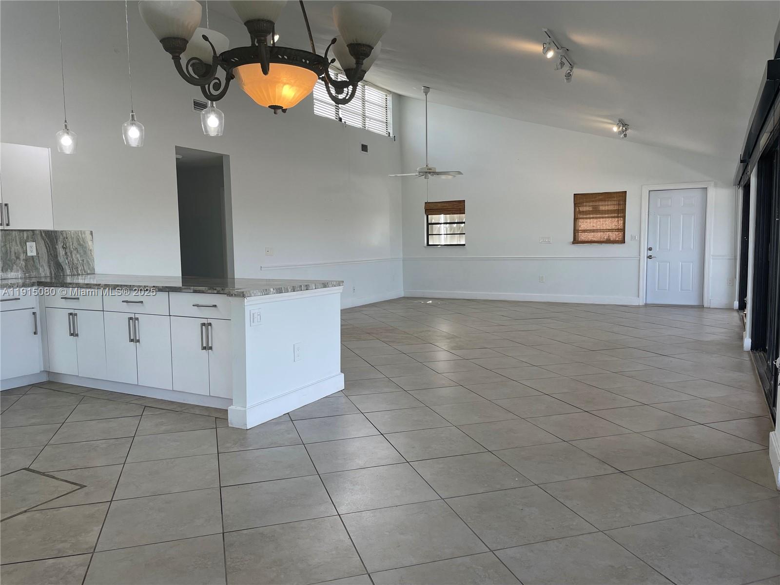 A spacious room features a kitchen island with stone countertops and white tile flooring — 26 S Exuma Rd # B, Key Largo FL 33037, KEY LARGO, FL