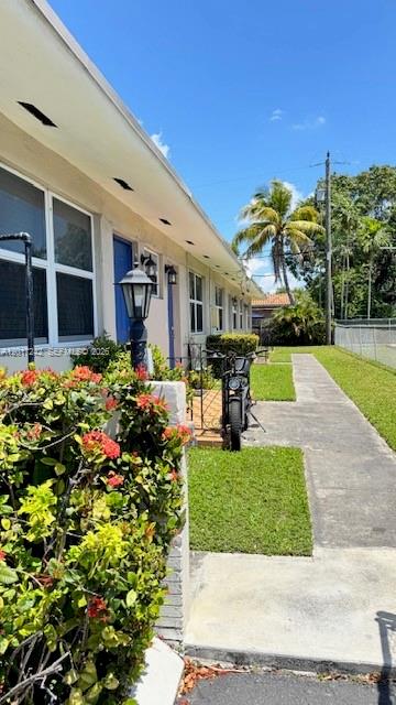 A view of a building exterior with a sidewalk, a parked motorcycle, and flowering bushes — 3085 W Flagler St # 2, Miami FL 33135, MIAMI, FL