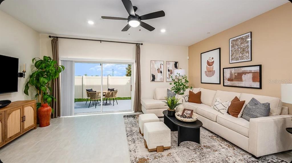 A living room features a beige sofa, a black coffee table, and a sliding glass door — 2631 BALMERINO WAY, MOUNT DORA, FL