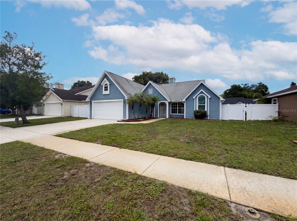A blue single-story house with a white garage door and a front lawn — 7221 HIDEAWAY TRAIL, NEW PORT RICHEY, FL