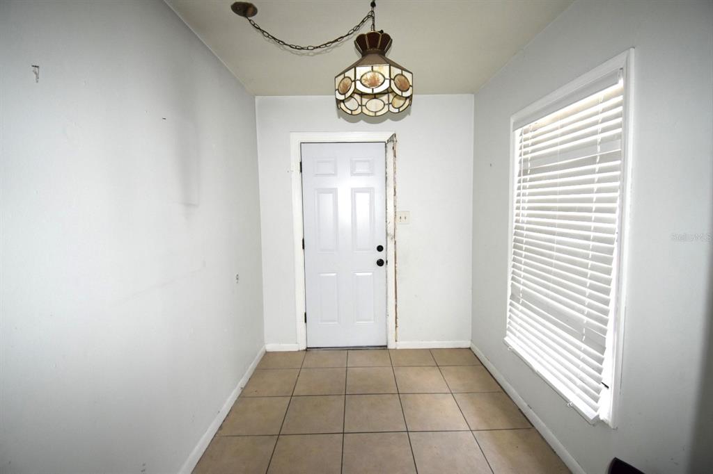 An entryway with light-colored walls, tiled flooring, a hanging light fixture, and a white door — 204 SHORE DRIVE W, OLDSMAR, FL