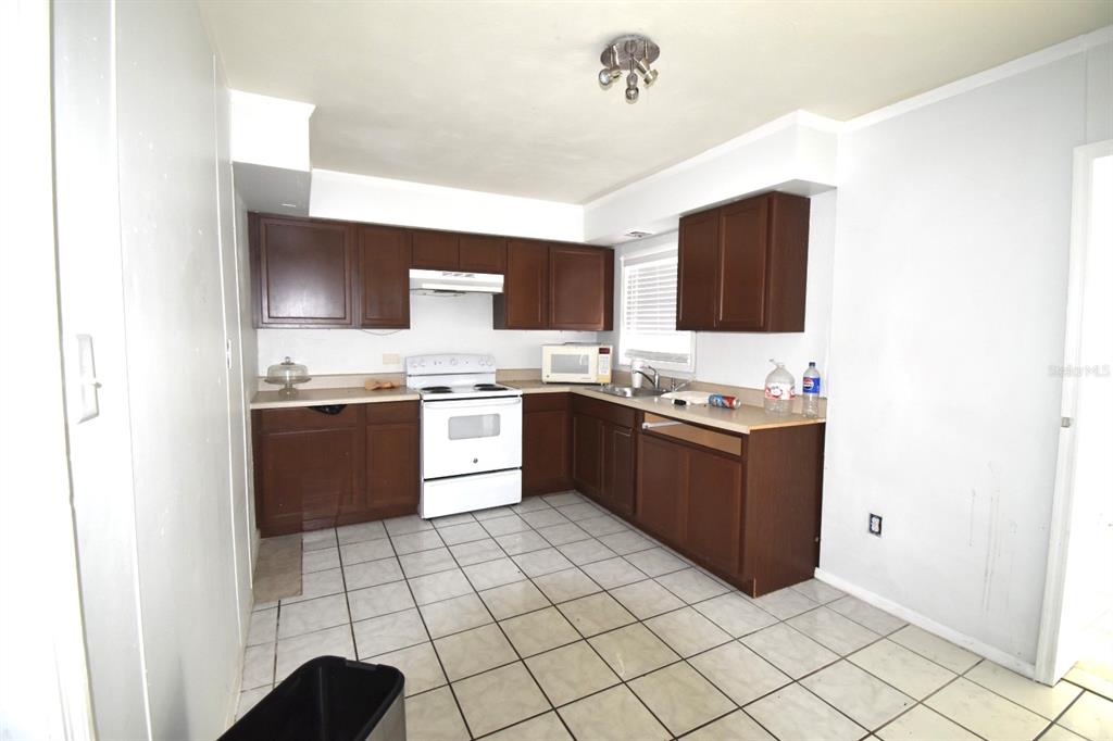 A kitchen with dark wood cabinets, white appliances, and light-colored tile flooring — 204 SHORE DRIVE W, OLDSMAR, FL