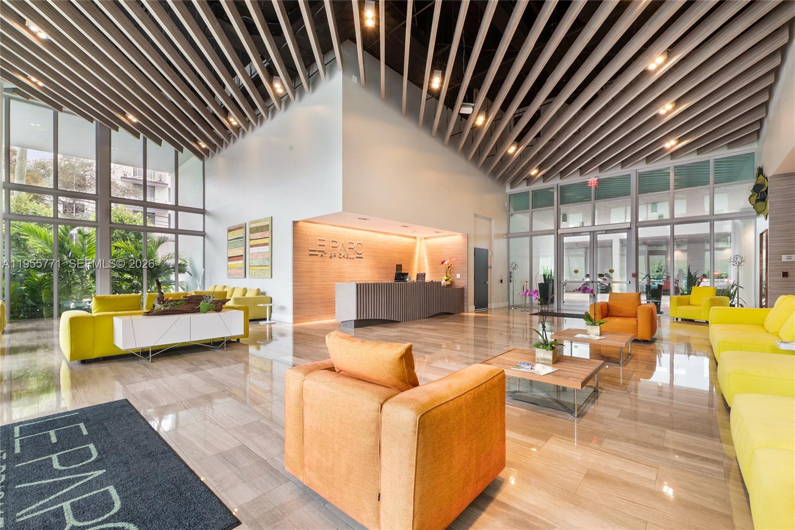 A modern lobby features a reception desk, yellow seating, and a slatted wood ceiling — 1600 SW 1st Ave # 707, Miami FL 33129, MIAMI, FL