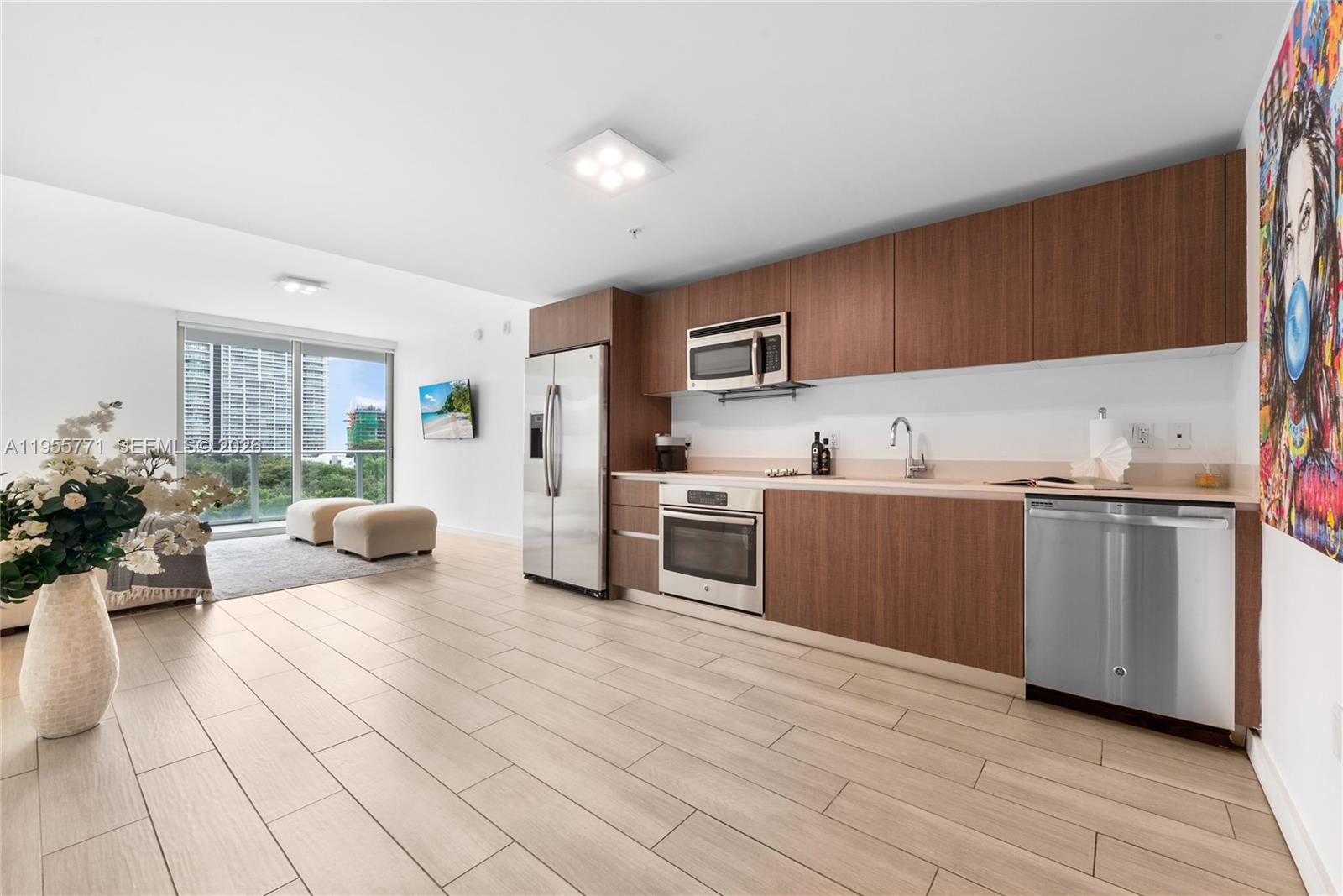 A modern kitchen with wood cabinets and stainless steel appliances opens to a living area — 1600 SW 1st Ave # 707, Miami FL 33129, MIAMI, FL