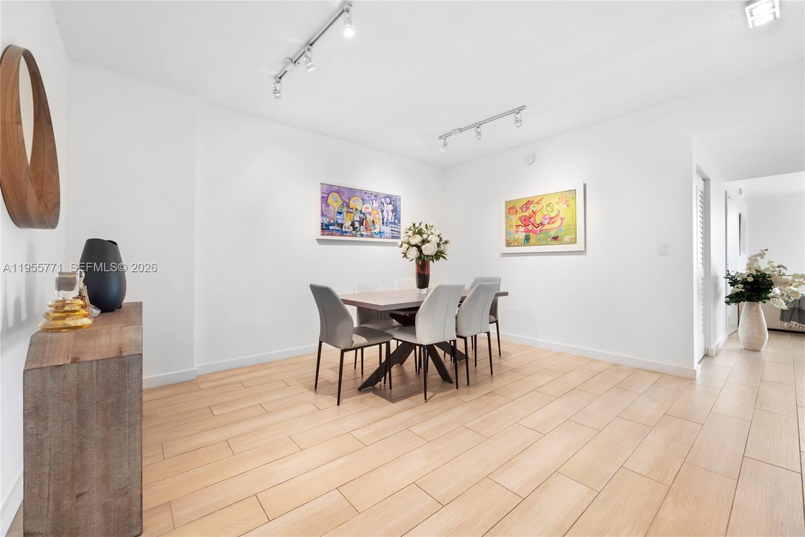 A dining room features a wooden table, six chairs, track lighting, and light wood flooring — 1600 SW 1st Ave # 707, Miami FL 33129, MIAMI, FL