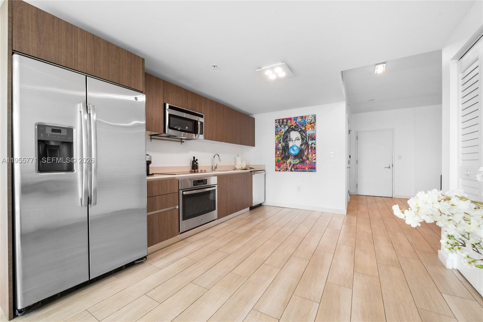 A modern kitchen features wood-toned cabinets, stainless steel appliances, and light wood-look tile flooring — 1600 SW 1st Ave # 707, Miami FL 33129, MIAMI, FL