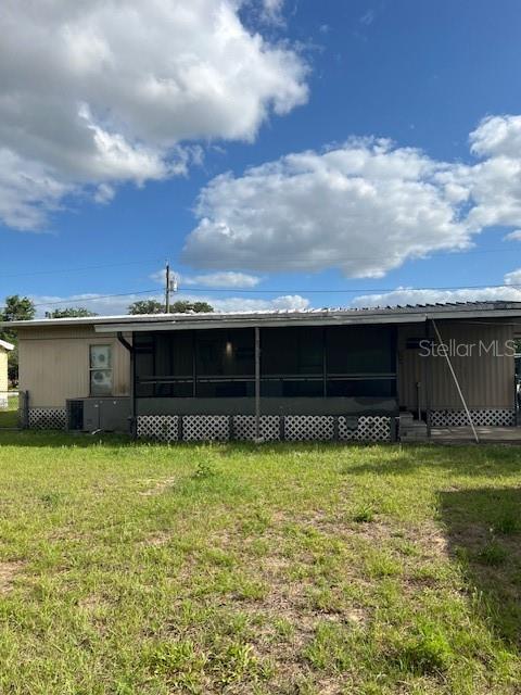 The exterior of a single-story home features a screened-in porch and lattice skirting — 9635 SE 162ND STREET, SUMMERFIELD, FL