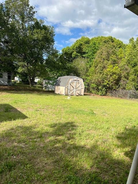 A backyard features a grassy lawn, a small storage shed, and surrounding trees — 9635 SE 162ND STREET, SUMMERFIELD, FL
