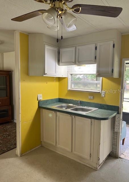 A kitchen features a double-basin sink, white cabinets, and bright yellow walls — 9635 SE 162ND STREET, SUMMERFIELD, FL