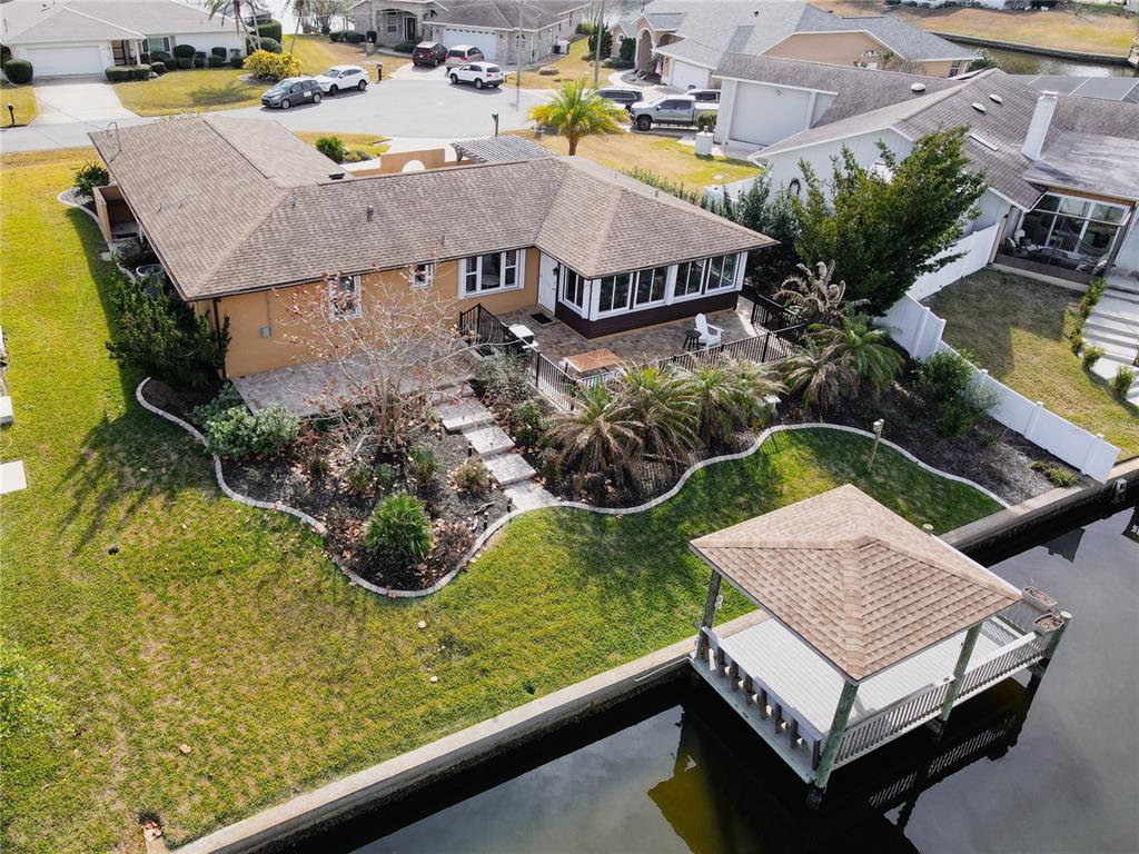 An aerial view shows a house with a patio, landscaping, and a dock on a canal — 12 COLLINSON COURT, PALM COAST, FL