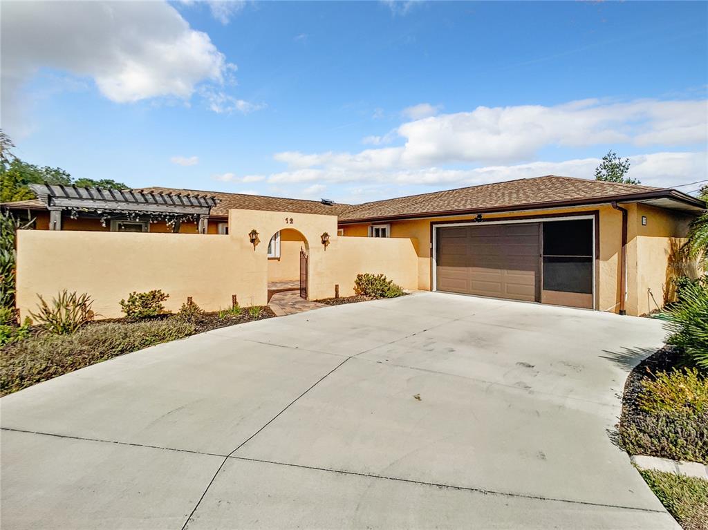 A single-story house with a beige stucco exterior, a gated courtyard, and a two-car garage — 12 COLLINSON COURT, PALM COAST, FL
