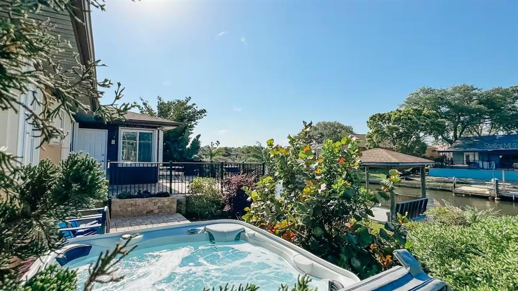 A hot tub sits on a patio overlooking a canal with a dock and houses — 12 COLLINSON COURT, PALM COAST, FL