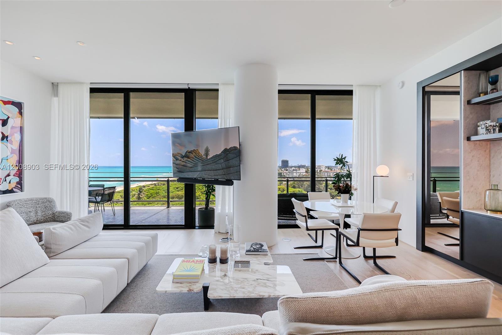 A modern living and dining area features floor-to-ceiling windows with ocean views and marble furniture — 8701 Collins Ave # 904, Miami Beach FL 33154, MIAMI BEACH, FL