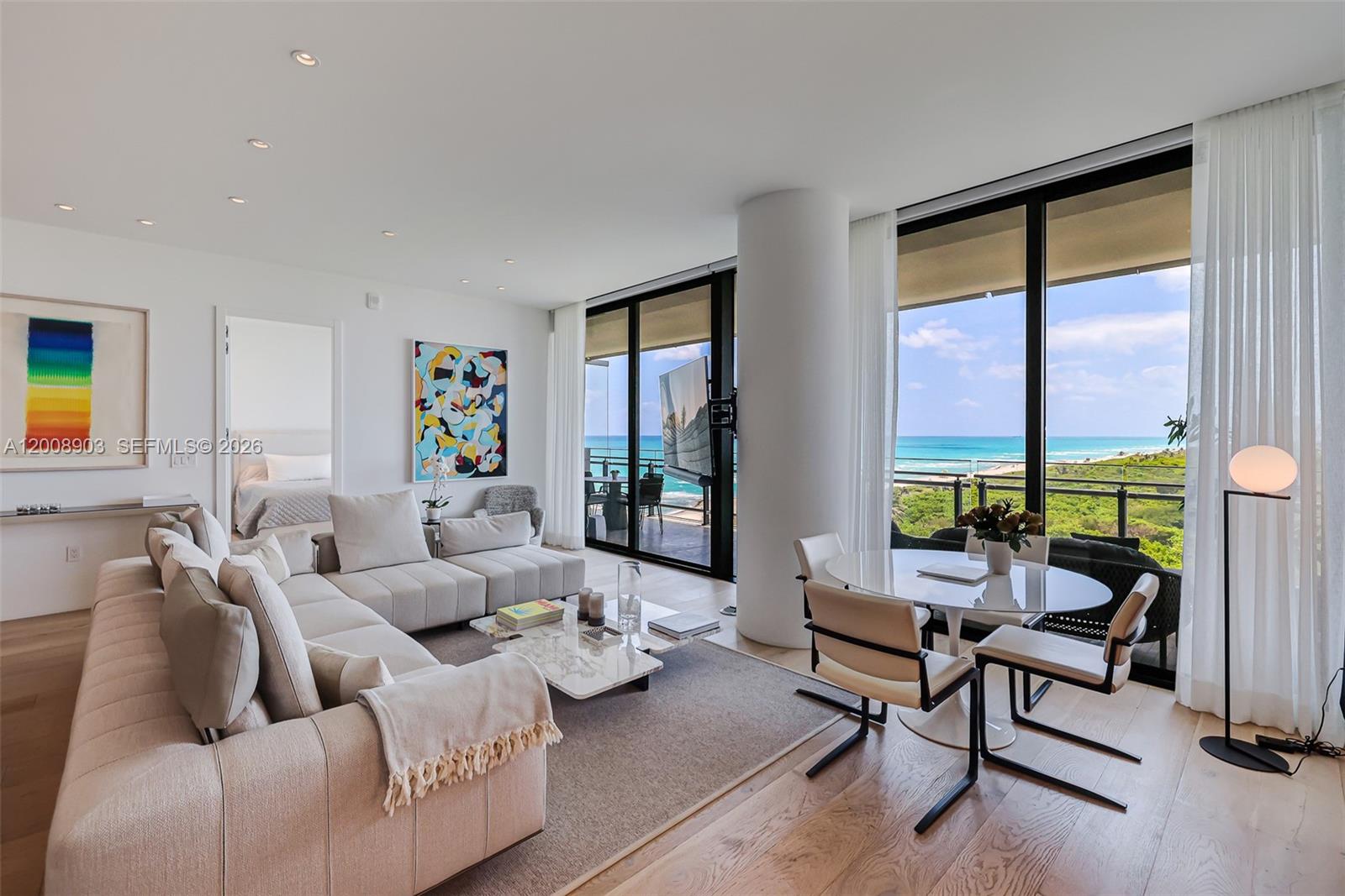 A modern living and dining area features a sectional sofa, floor-to-ceiling windows, and ocean views — 8701 Collins Ave # 904, Miami Beach FL 33154, MIAMI BEACH, FL