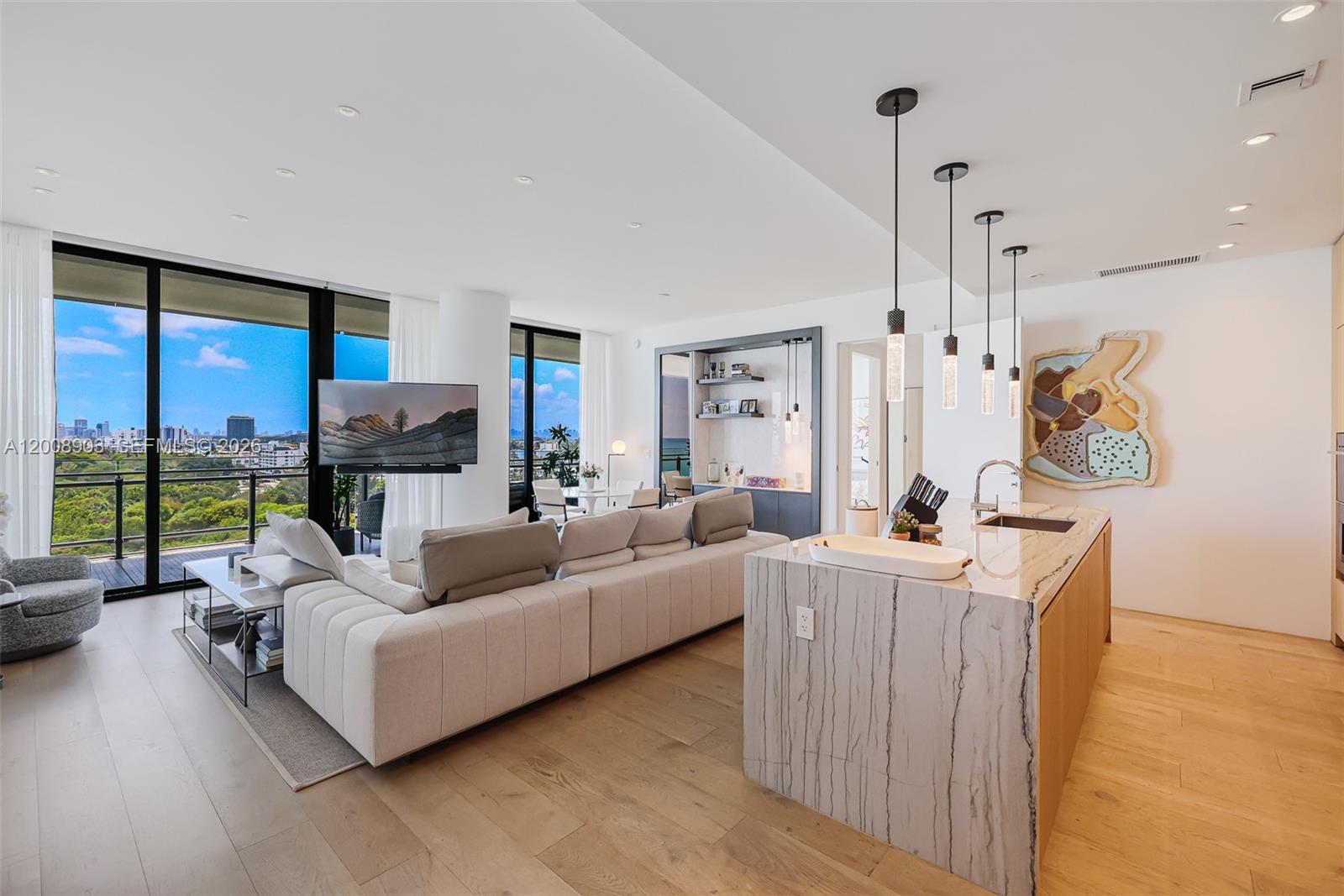 An open-concept living area features a kitchen island, a sectional sofa, and floor-to-ceiling windows — 8701 Collins Ave # 904, Miami Beach FL 33154, MIAMI BEACH, FL