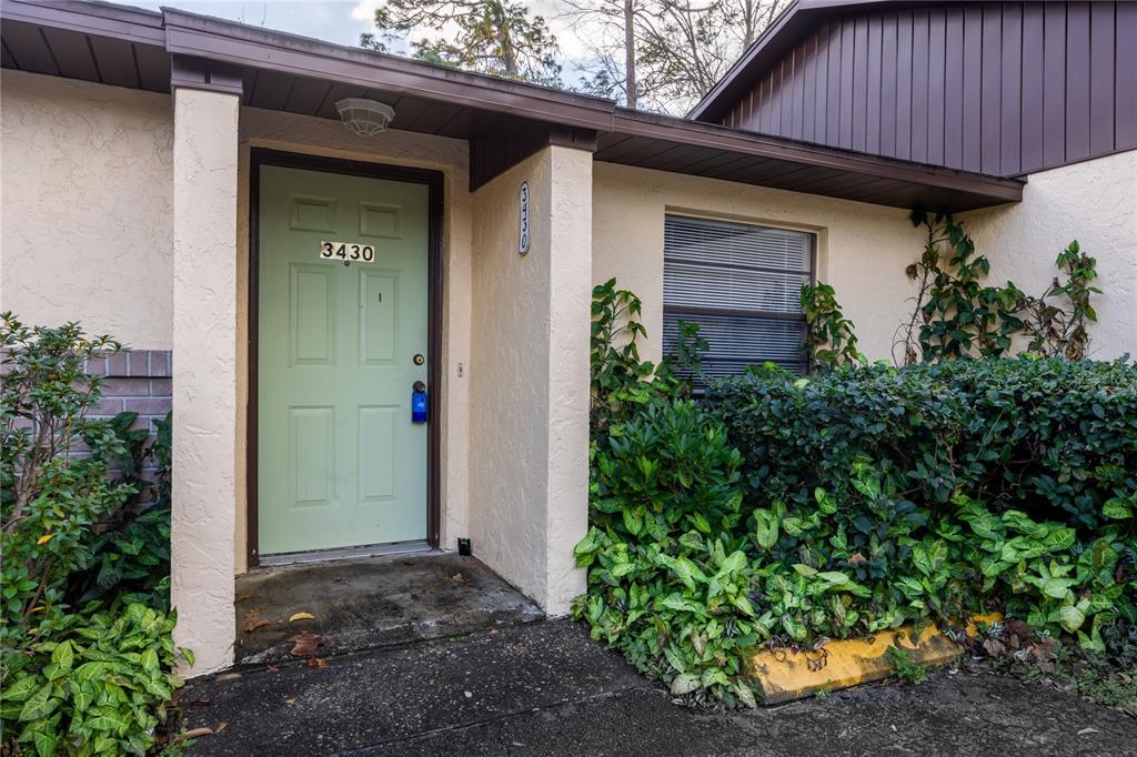 A light green front door with the number 3430 sits beside a window and landscaping — 3430 NW 21ST DRIVE UNIT D-2, GAINESVILLE, FL