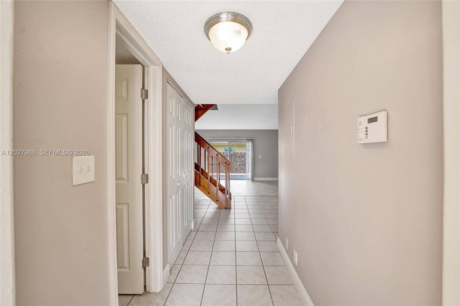 A tiled hallway leads to a wooden staircase and a living area with sliding doors — 7175 Nova Dr # 107, Davie FL 33317, DAVIE, FL