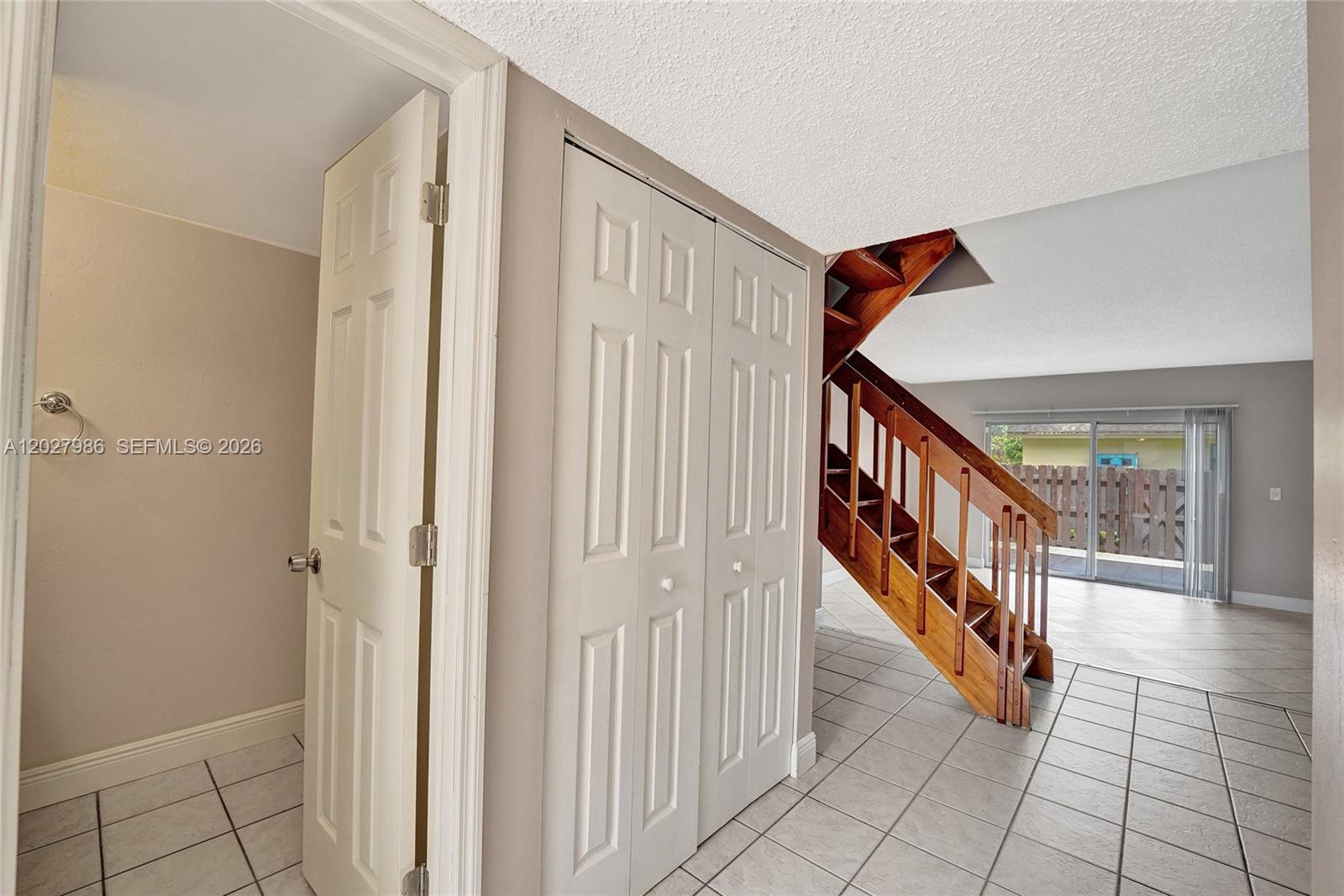 A tiled entryway features a wooden staircase, a closet, and a doorway leading to another room — 7175 Nova Dr # 107, Davie FL 33317, DAVIE, FL