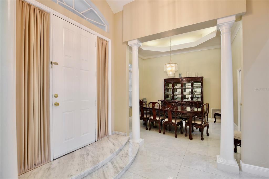 A foyer with a marble step leads into a dining room featuring white columns — 9374 WICKHAM WAY, ORLANDO, FL