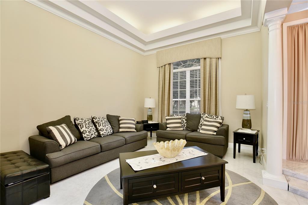 A living room features two dark sofas, a coffee table, and a tray ceiling — 9374 WICKHAM WAY, ORLANDO, FL