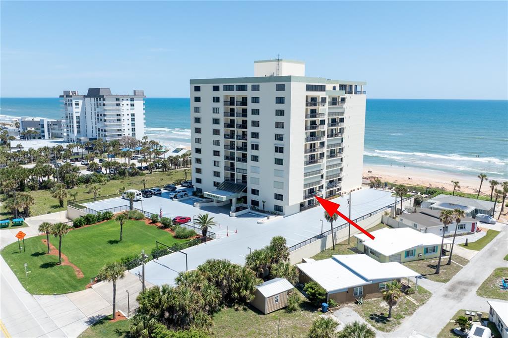 An aerial view shows a multi-story beachfront condominium building with a red arrow pointing to a balcony — 1513 OCEAN SHORE BOULEVARD UNIT 2C, ORMOND BEACH, FL