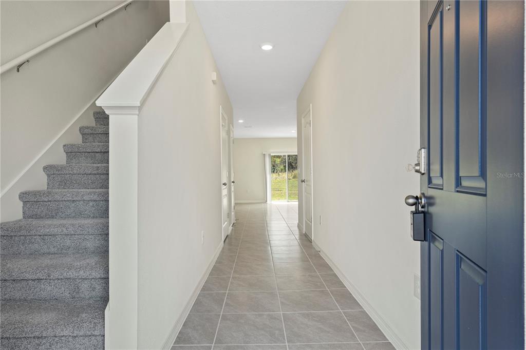 An entryway features a carpeted staircase on the left, tiled flooring, and a blue front door — 3176 GOOSE ROAD, DAVENPORT, FL