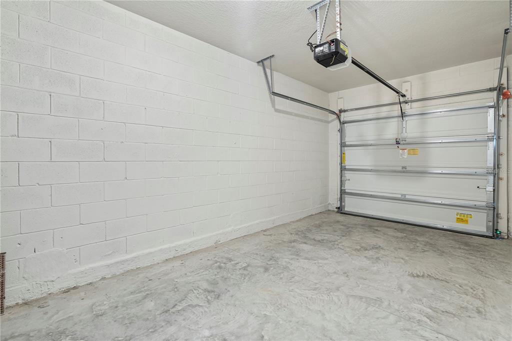 An empty garage features white painted concrete block walls and a concrete floor — 3176 GOOSE ROAD, DAVENPORT, FL