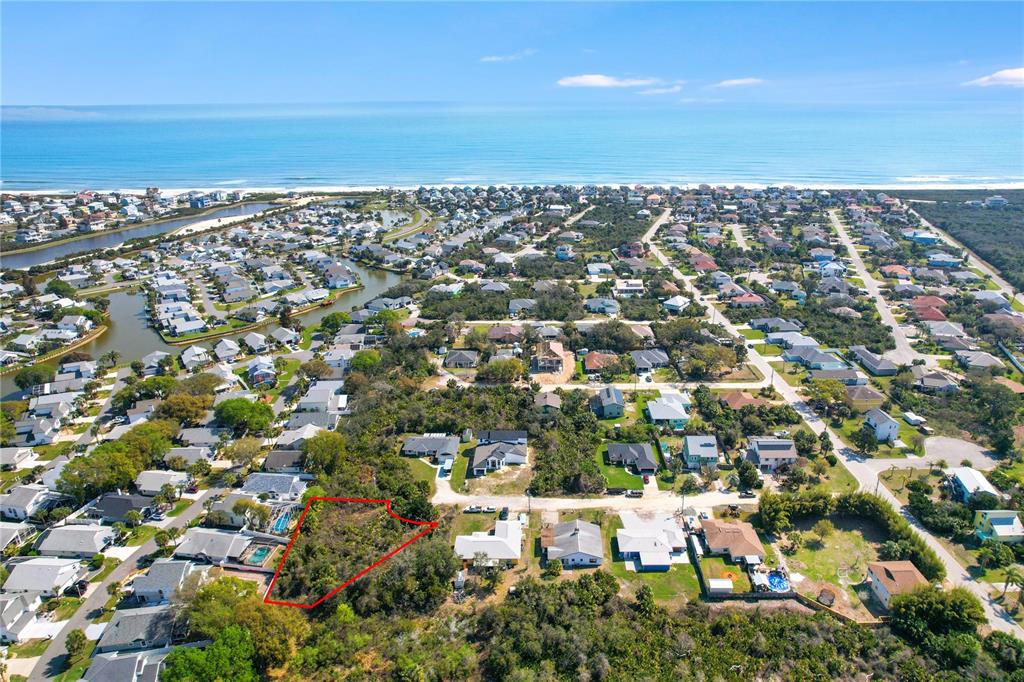 An aerial view shows a vacant, wooded lot outlined in red within a coastal neighborhood — 14 SWEETBAY DRIVE, PALM COAST, FL