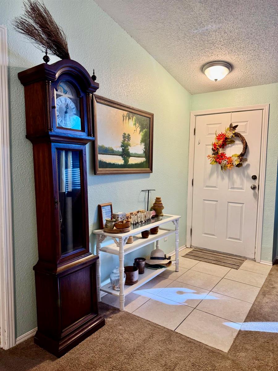 An entryway features a tall wooden grandfather clock, a console table, and a front door — 2091 SE 24th Boulevard, Okeechobee FL 34974, OKEECHOBEE, FL