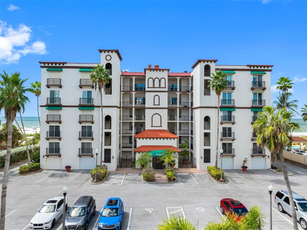 A multi-story apartment building with balconies and a parking lot in the foreground — 200 121ST AVENUE UNIT 104, TREASURE ISLAND, FL
