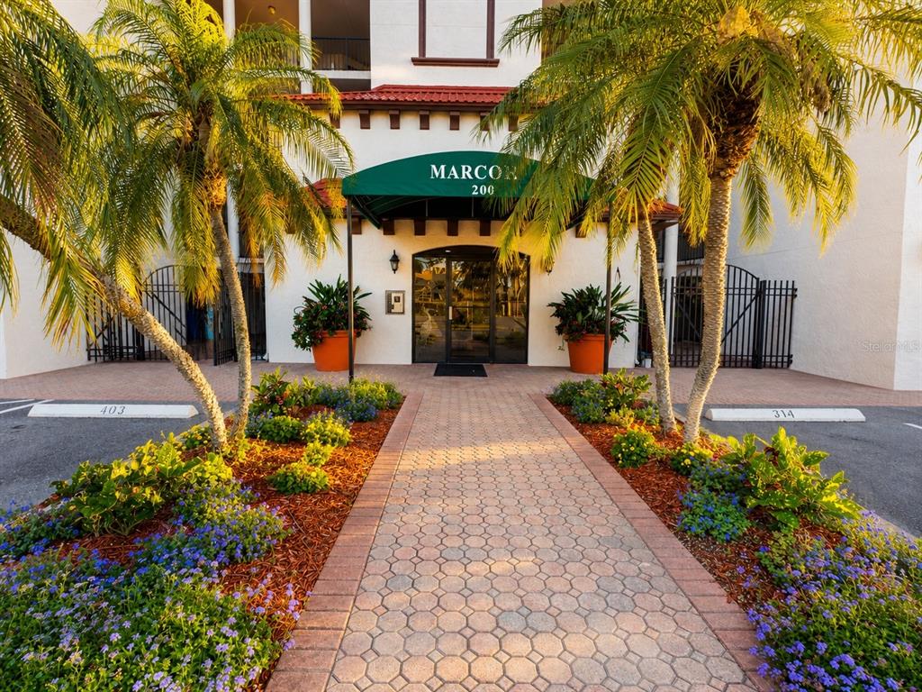A paved walkway leads to the entrance of a building with a green awning — 200 121ST AVENUE UNIT 104, TREASURE ISLAND, FL