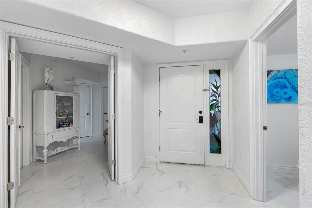 A white-tiled entryway features a front door with a stained-glass panel and an open doorway — 200 121ST AVENUE UNIT 104, TREASURE ISLAND, FL
