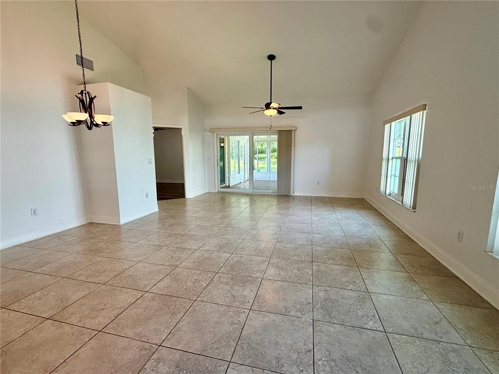 A spacious living room features light tile flooring, vaulted ceilings, and sliding glass doors — 2461 BENTLEY DRIVE, PALM HARBOR, FL