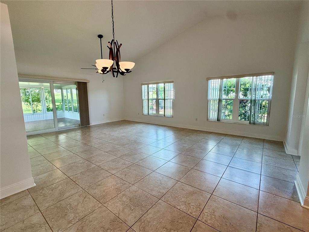 A spacious living room features vaulted ceilings, tile flooring, a chandelier, and large windows — 2461 BENTLEY DRIVE, PALM HARBOR, FL