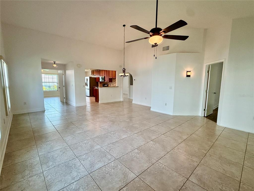 A spacious living area with tile floors, a ceiling fan, and an open kitchen beyond — 2461 BENTLEY DRIVE, PALM HARBOR, FL