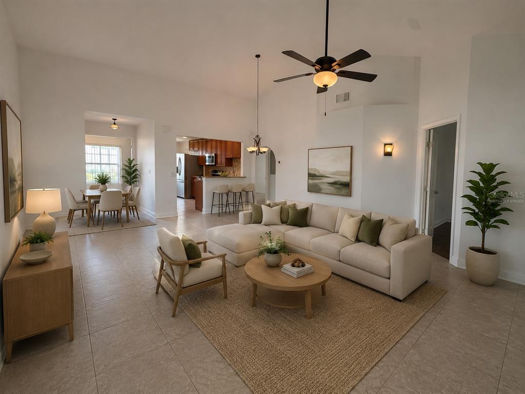 A living room with a sectional sofa, coffee table, and adjacent dining area with tile floors — 2461 BENTLEY DRIVE, PALM HARBOR, FL