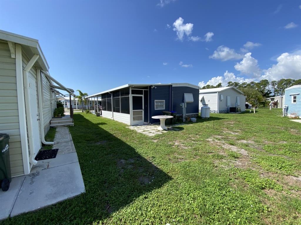 An exterior view of mobile homes with a screened-in porch and a grassy yard — 6427 KEENA COURT, NORTH PORT, FL