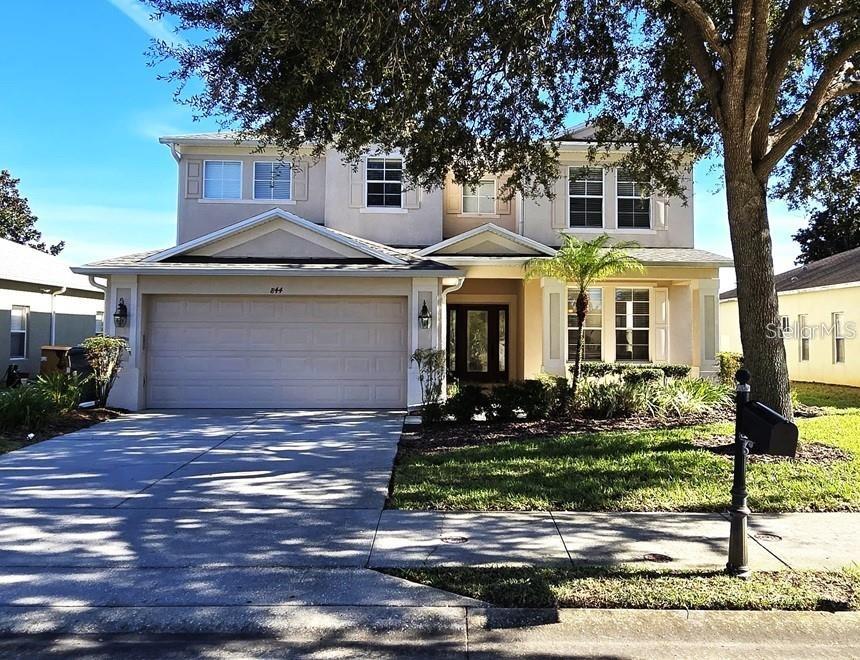 A two-story suburban house with a beige exterior, a two-car garage, and a front lawn — 844 SUFFOLK PLACE, DAVENPORT, FL