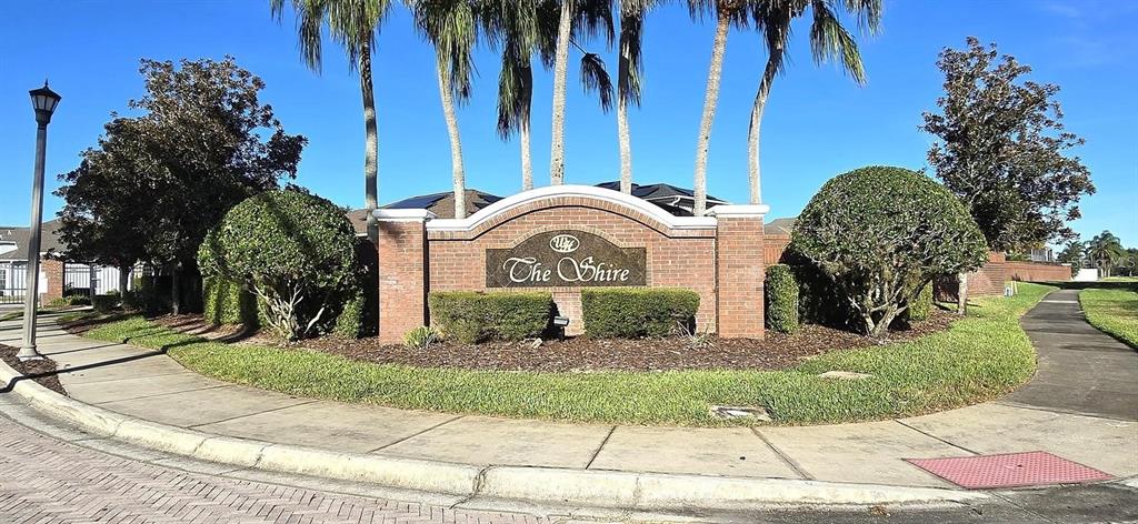 A brick monument sign for The Shire stands at a street corner with palm trees — 844 SUFFOLK PLACE, DAVENPORT, FL