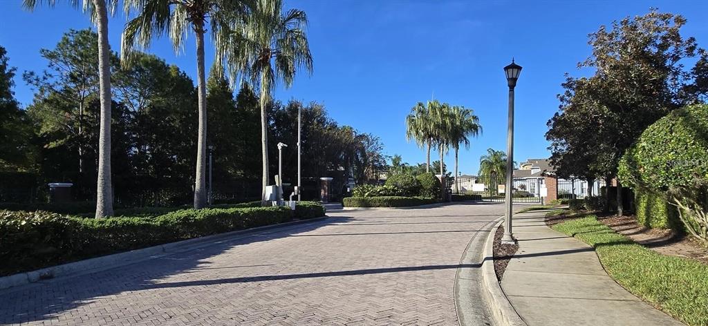 A paved driveway leads to the gated entrance of a residential community with palm trees — 844 SUFFOLK PLACE, DAVENPORT, FL